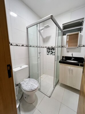 Une salle de bain avec une douche à parois de verre, des toilettes et un lavabo avec un miroir au-dessus.