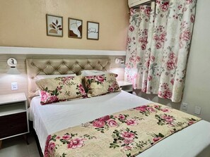 A bedroom with a tufted headboard, floral bedding, and curtains. - 102 Welcoming and cozy (Belém)