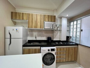 A compact kitchen with a refrigerator, microwave, stove, and washing machine. - 102 Welcoming and cozy (Belém)