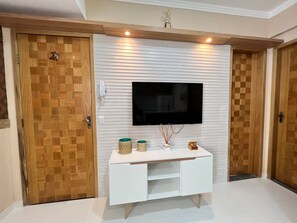 A room with a white console table, a mounted TV, and two wooden doors. - 102 Welcoming and cozy (Belém)
