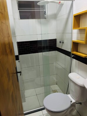 Ein Badezimmer mit einer gläsernen Duschkabine, einer Toilette und einem Holzboden.