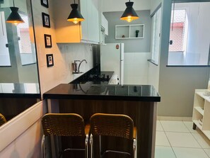 A kitchen with a central island, two wicker chairs, pendant lights, and a refrigerator. - 103 Beautiful and Delicate Apartment (Belém)