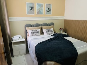 A hotel room with a bed, two pillows with motivational text, a bedside table with a phone and towels, and a wall with three framed artworks. - 103 Beautiful and Delicate Apartment (Belém)