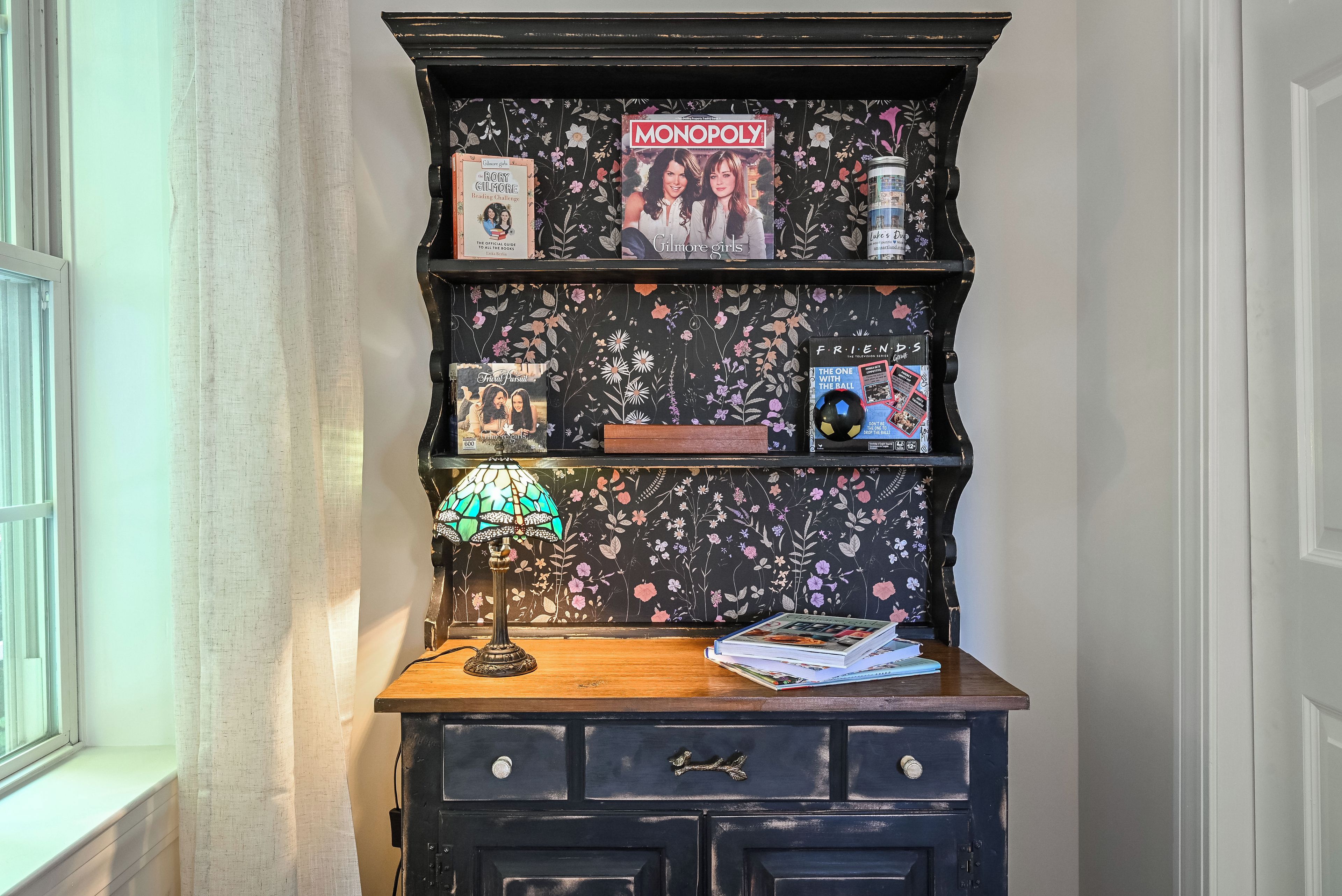 A bookshelf with various items including a Monopoly game, a lamp, and books.