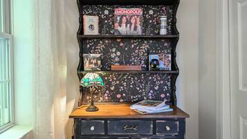 A bookshelf with various items including a Monopoly game, a lamp, and books.