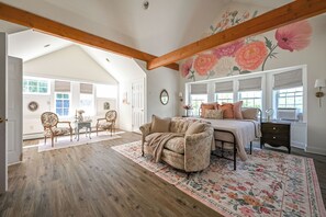 Un dormitorio con una cama grande, papel tapiz floral, techo de madera y vistas al exterior.