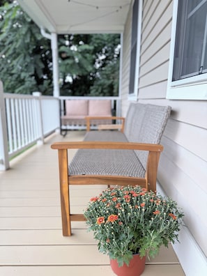 Een houten bank op een veranda, met een bloempot ervoor.
