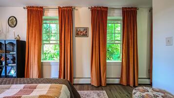 A bedroom with a bed, a dresser, and a window with curtains.