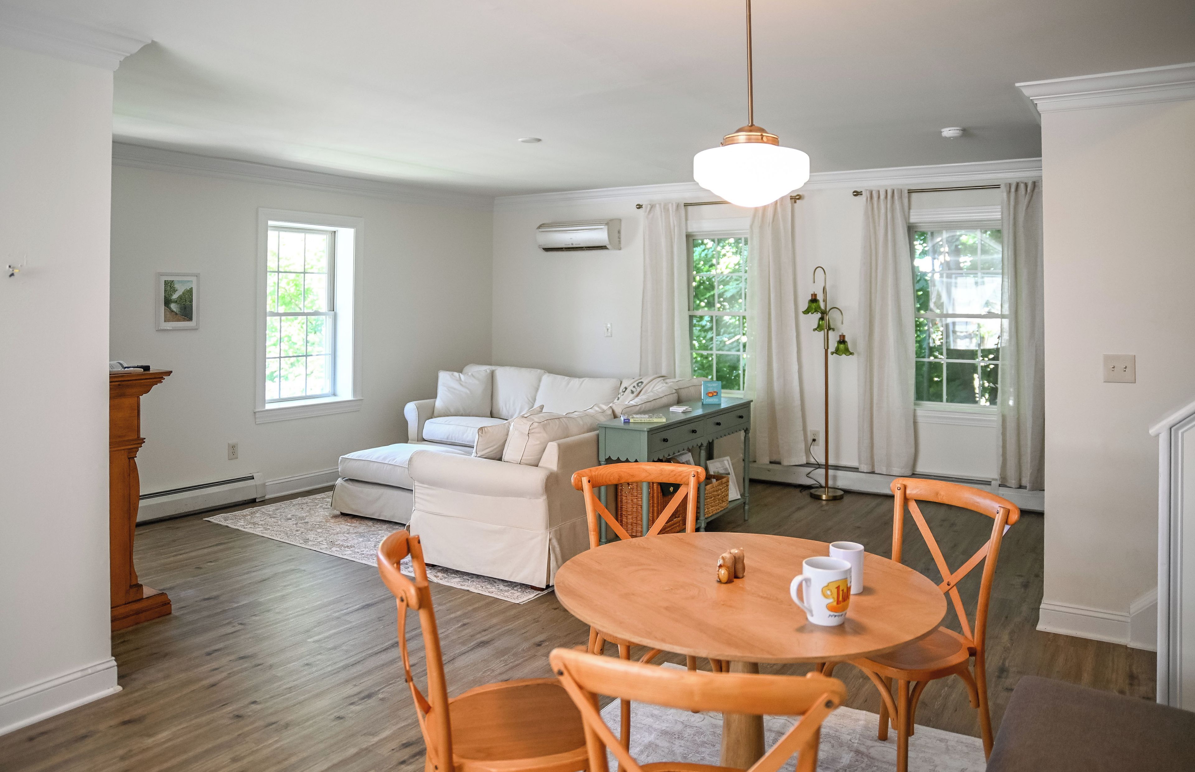 A dining area with a round wooden table and chairs, a sofa, and a pendant light.