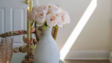 A room with a table featuring a vase of flowers, a candle, and a glass.