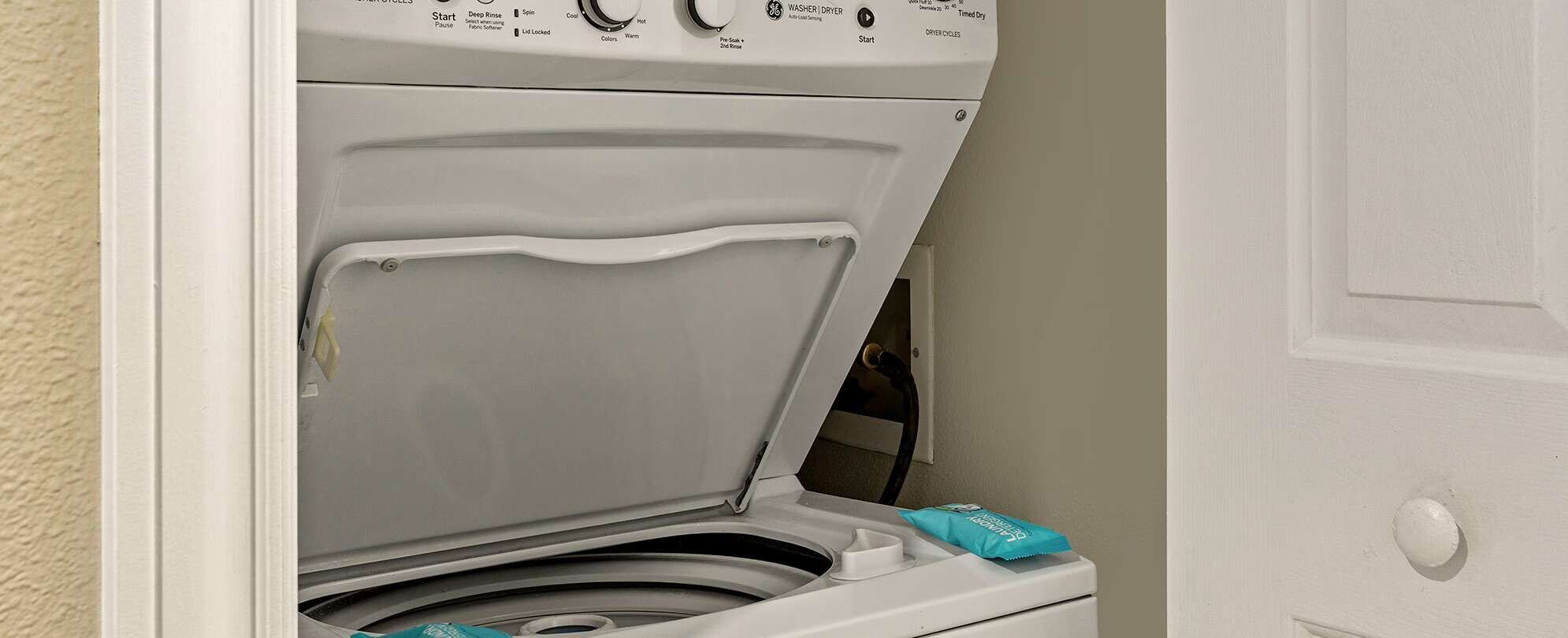 Une machine à laver blanche, dotée d’un panneau de commande, d’une porte et d’un distributeur de serviettes.