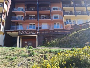 Ein mehrstöckiges Wohngebäude mit Balkonen, einer Treppe und einer Rasenfläche mit gelben Blumen.