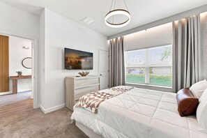 A modern bedroom with a large bed, a flat-screen TV, a desk, and a window with curtains. - Chic Disney Escape, Themed Rooms & Private Pool (Four Corners)