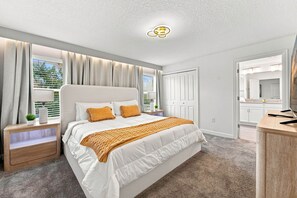 A bedroom with a large bed, bedside tables, a wardrobe, and a mirror. - Chic Disney Retreat with Fun Themed Rooms (Four Corners)