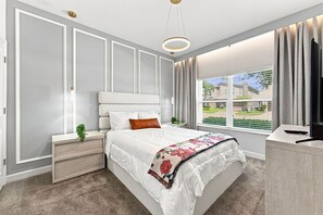 Un dormitorio moderno con una cama grande, una mesita de noche, un aparador y un ventanal con vistas.