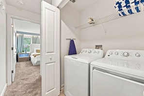 A laundry room with two white washing machines, a drying rack, and a window with curtains. - Chic Disney Retreat with Fun Themed Rooms (Four Corners)