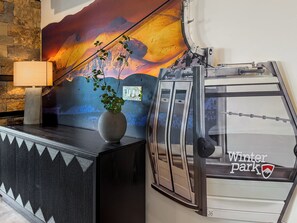A reception desk with a lamp, a vase with a plant, a wall mural, and a ski lift. - Sleeps 18 | 2 Hot Tubs, Sauna & Game Room (Winter Park)