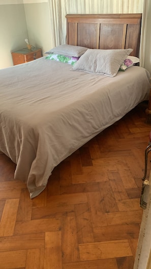 Ein Bett mit einem Holz-Kopfteil, einer gemusterten Tagesdecke und einem einzelnen Zierkissen.