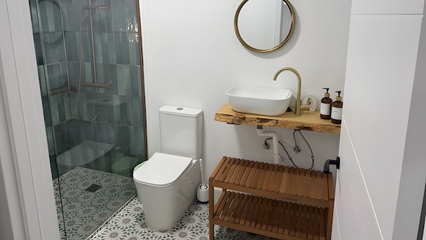 Ein Badezimmer mit Duschkabine aus Glas, einer weißen Toilette, einem Holzlagerfeld mit Waschbecken und einem Spiegel.