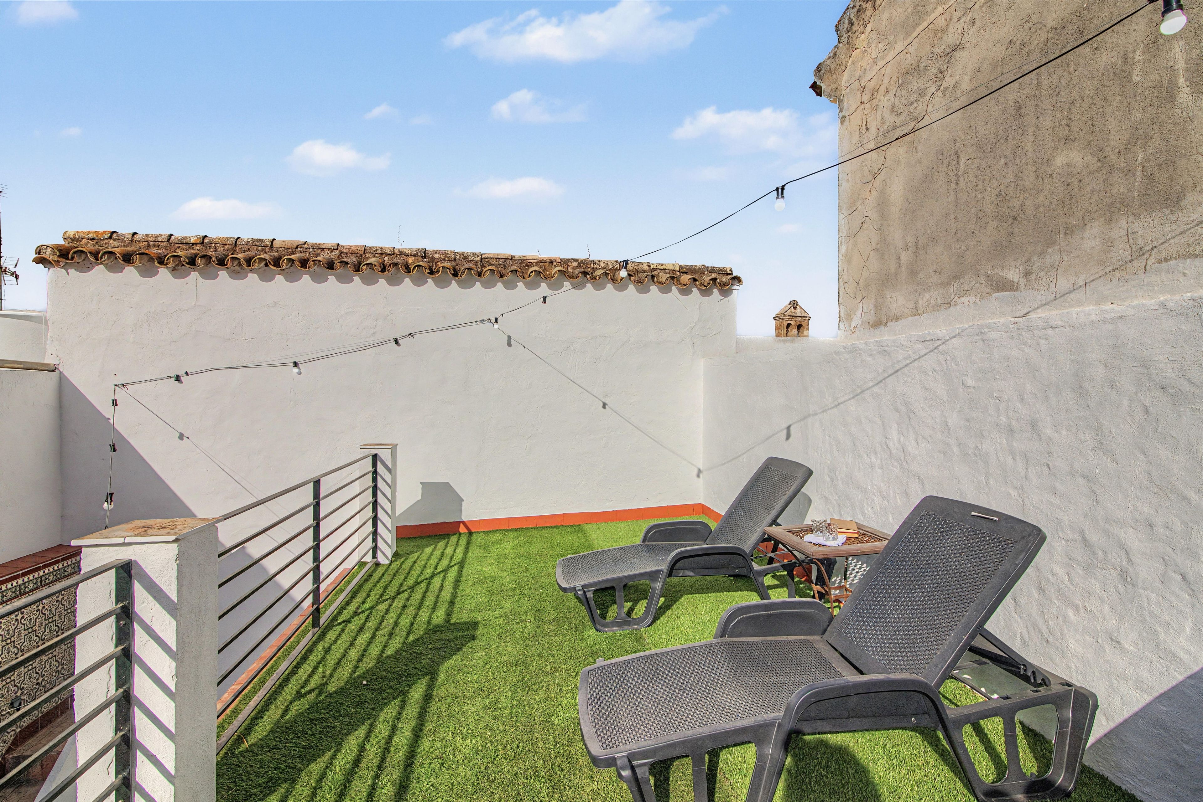Terraza en la azotea con mobiliario exterior y vistas a un edificio histórico.