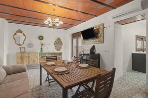 A dining area with a wooden table set for four, surrounded by chairs, a chandelier, and decorative mirrors on the walls. - Vacation Home 'La Casa del Castillo' with Private Terrace, Wi-Fi & Air Conditioning (Niebla)