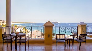 Un balcon avec vue sur la mer, comprenant une table, des chaises et une balustrade.
