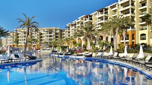 Un hôtel doté d’une grande piscine, de nombreux balcons et de palmiers.