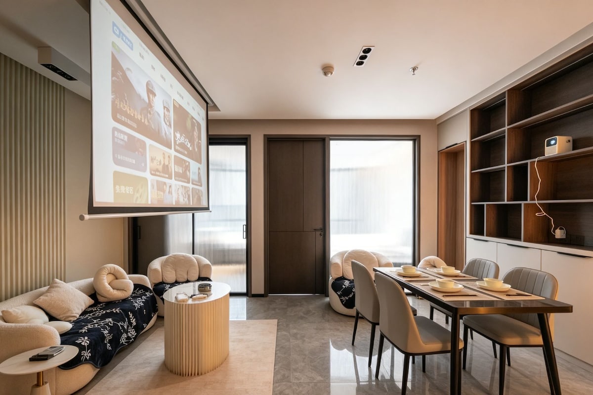 Un salon moderne comprenant un canapé, une table basse, une table à manger avec des chaises, un écran de projection et une bibliothèque.