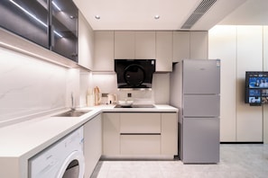 A modern kitchen with a built-in washing machine, a refrigerator, and a wall-mounted TV. - Shijia Homestay (Shanghai Lujiazui Century Avenue Branch) (Shanghai)