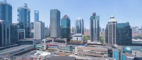A cityscape with modern skyscrapers, a large commercial building with signage, and a parking area.
