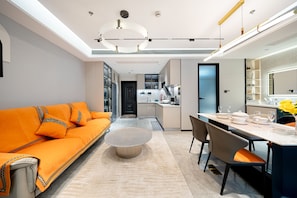 Un salon moderne avec un canapé, une table à manger dressée pour deux personnes et une cuisine en arrière-plan.