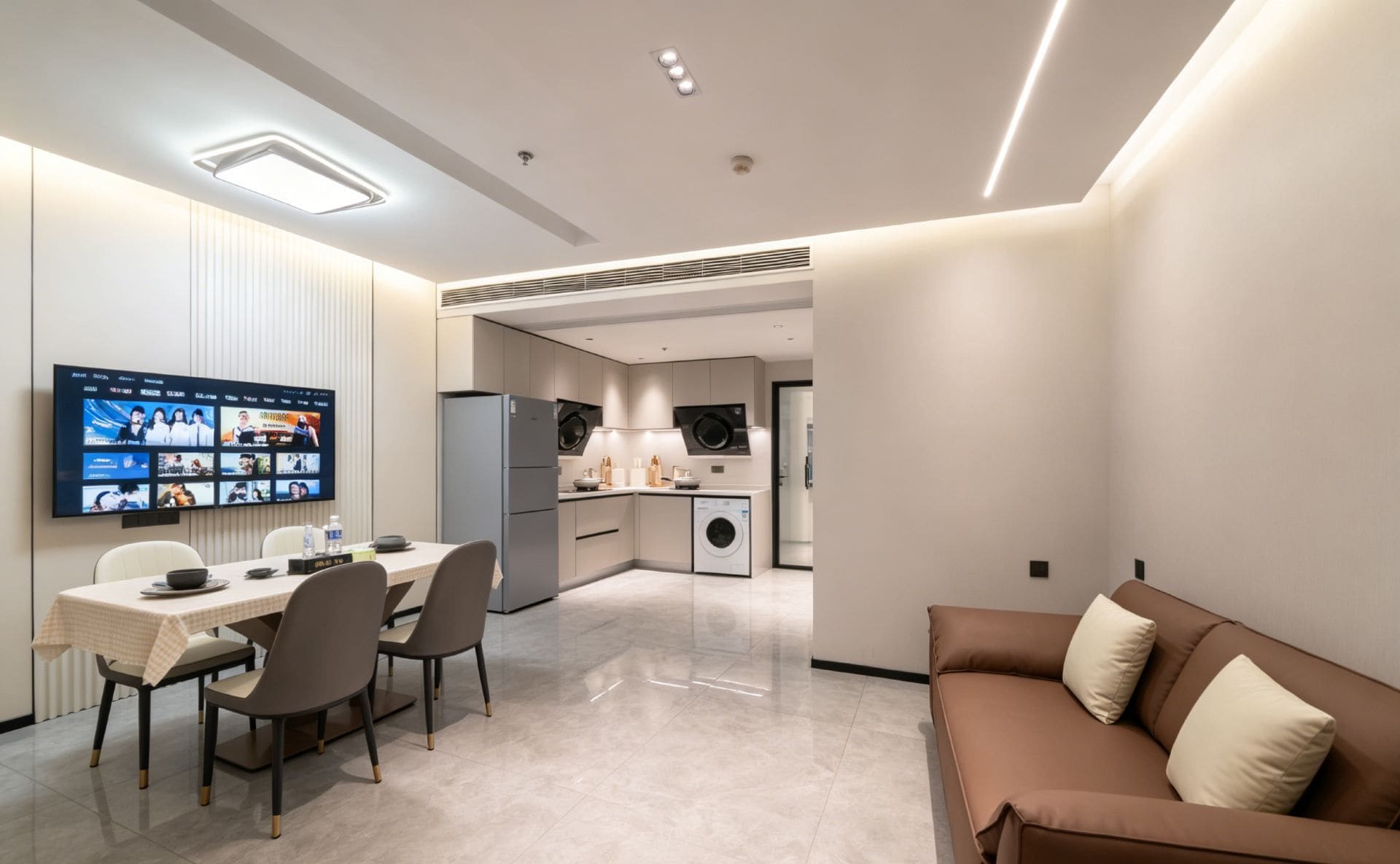 A modern hotel room with a dining area, kitchenette, and a sofa.