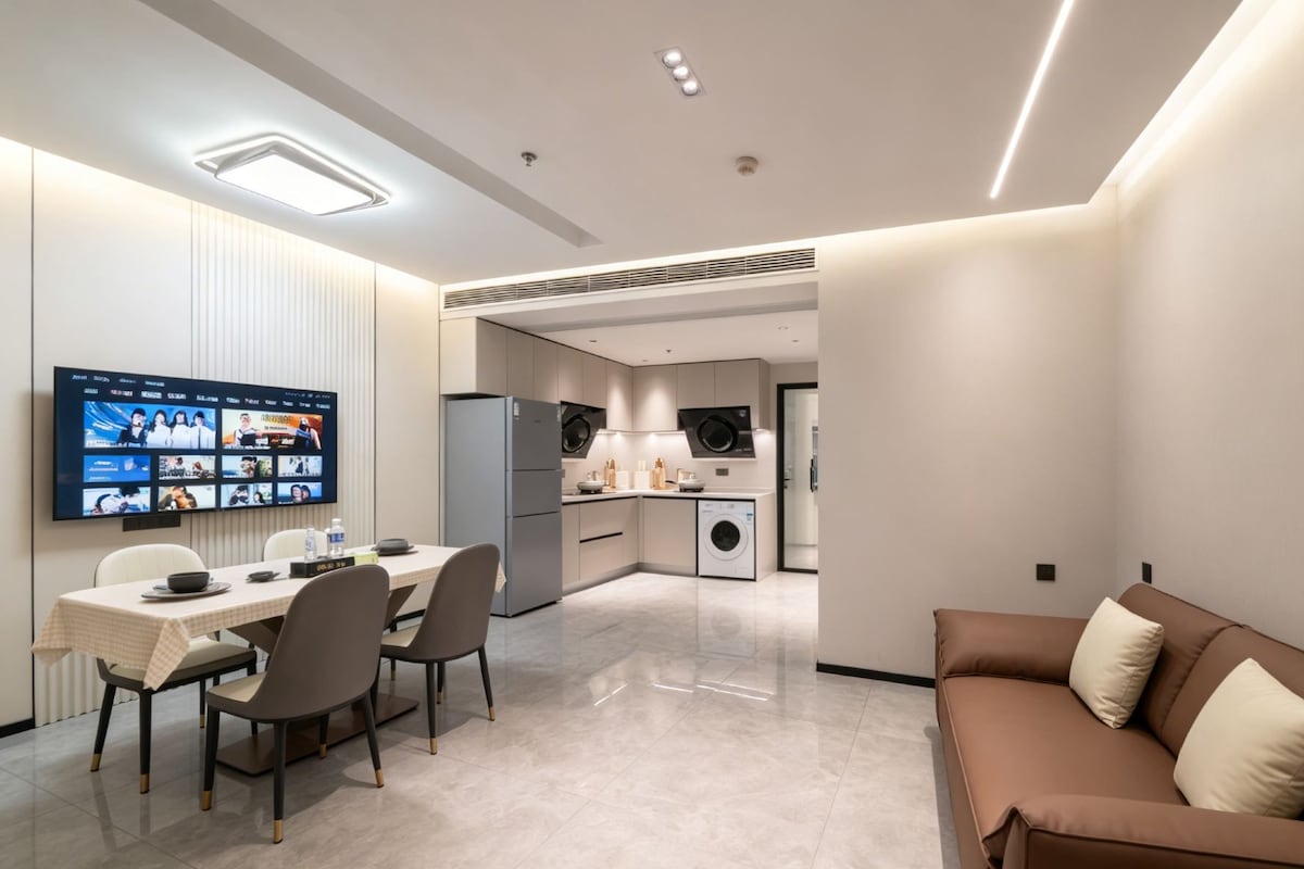 A modern hotel room with a dining area, kitchenette, and a sofa.