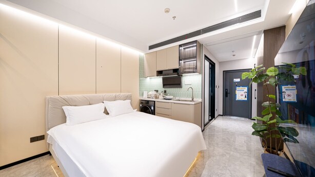 A hotel room with a bed, a small kitchenette, a bathroom, and a potted plant. - Shijia Homestay - Shanghai Century (Shanghai)