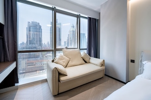 A modern hotel room with a sofa, a bed, and a large window offering a city view. - Shijia Homestay - Shanghai Century (Shanghai)