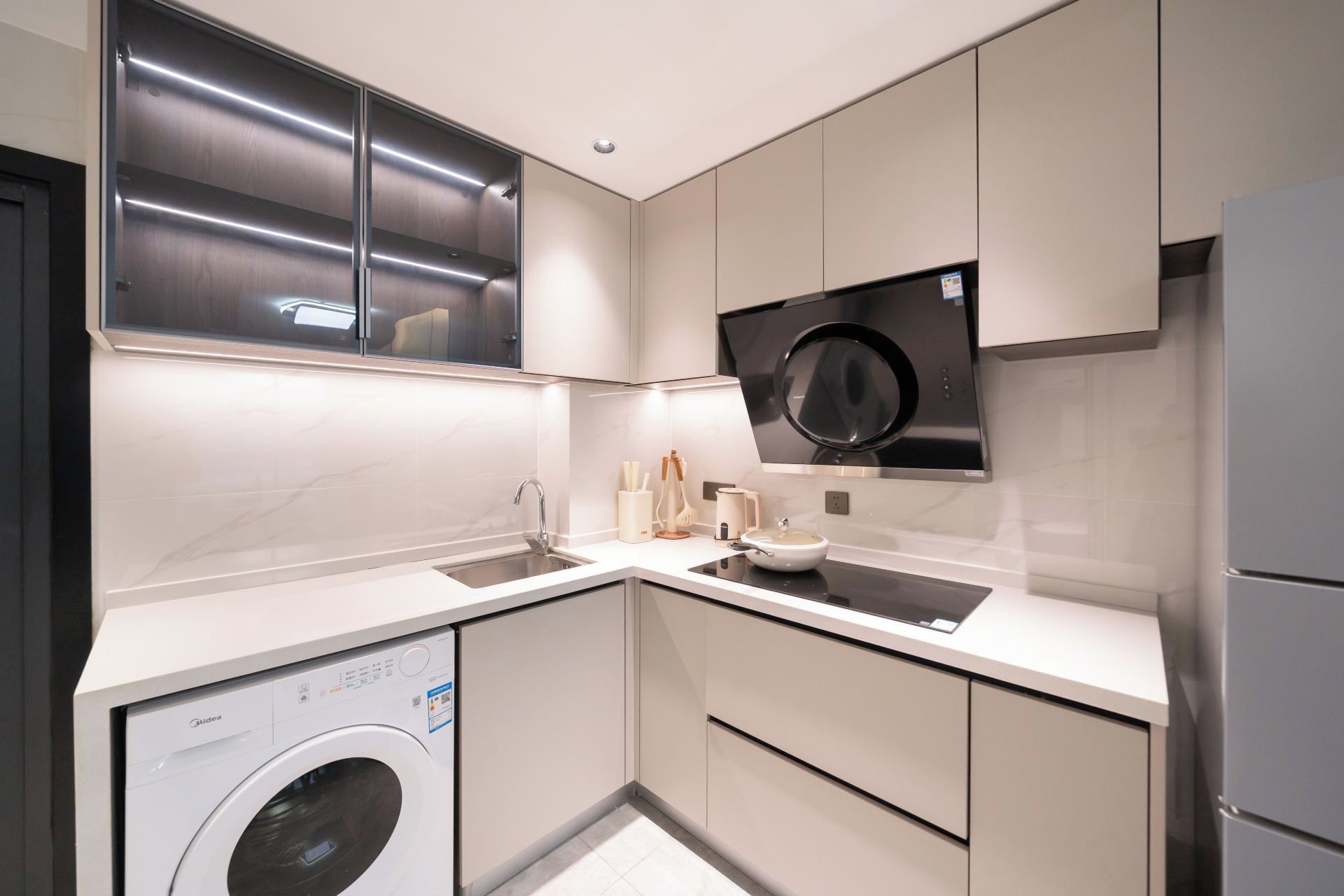 Une cuisine moderne équipée d’un lave-linge, d’un four à micro-ondes et d’un réfrigérateur.