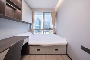 Una habitación de hotel con una cama, un escritorio y una ventana con vista a la ciudad.