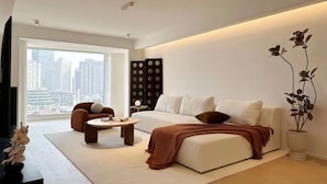 A modern living room with a sofa, two armchairs, a coffee table, and a large window offering a city view. - Shijia Homestay - Shanghai Century (Shanghai)