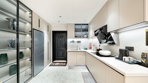A modern kitchen with a built-in refrigerator, a black door, and a countertop with various appliances and items. - Shijia Homestay - Shanghai Century (Shanghai)