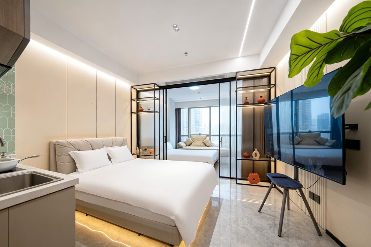 Une chambre d’hôtel moderne équipée d’un lit, d’une télévision, d’un bureau avec un lavabo et d’une grande fenêtre.