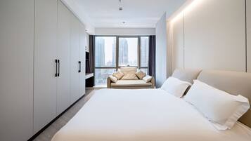 A modern hotel room with a large bed, a sofa, and a city view.