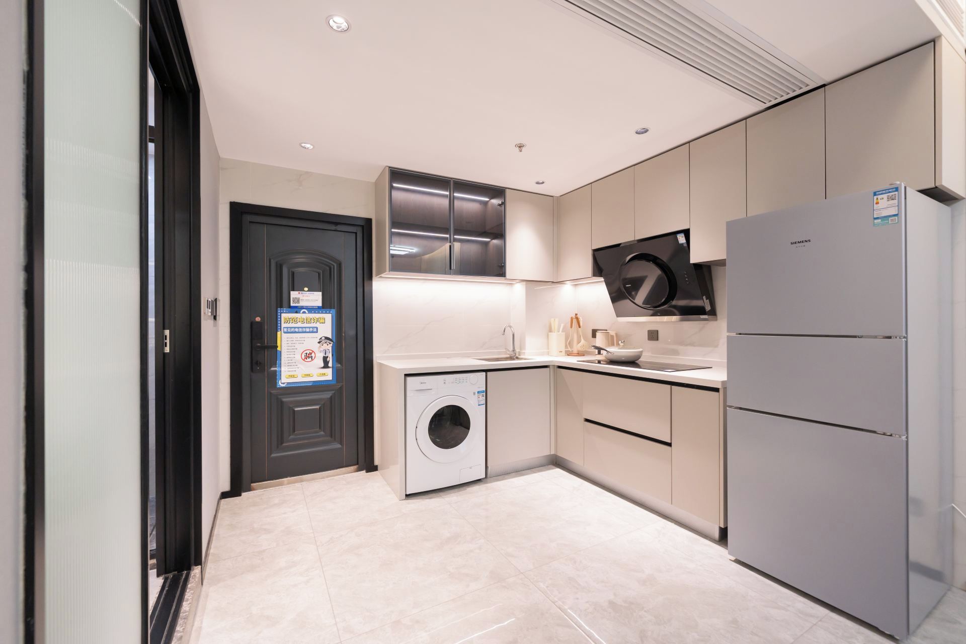 A modern kitchen with a washing machine, a Siemens refrigerator, and a microwave.