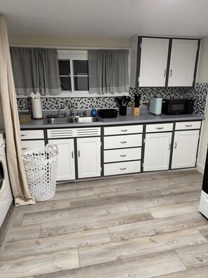 A kitchen with a sink, a microwave, and cabinets.