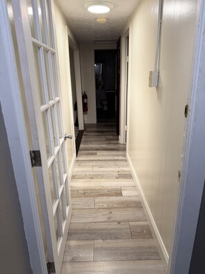 A hallway with wooden flooring, white walls, and a ceiling light.