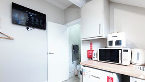 Eine moderne Küche mit Mikrowelle, Toaster und kleinem Kühlschrank. Ein digitales Display zeigt ein Menü zur Sprachauswahl an.
