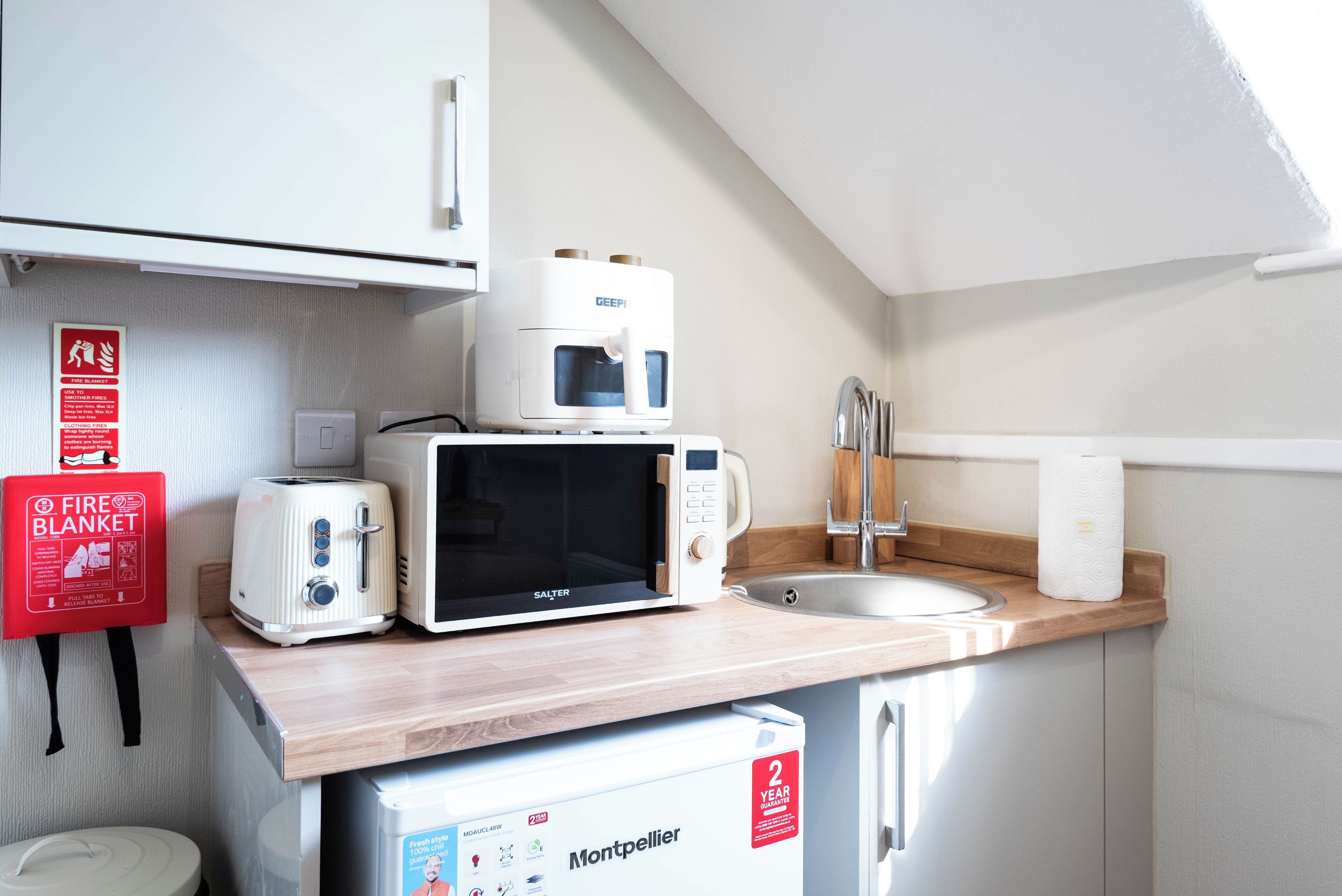 Una kitchenette equipada con microondas, tostadora y refrigerador.