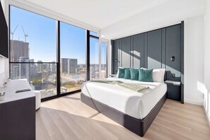 A modern bedroom with a large bed, a desk, and a view of the cityscape through floor-to-ceiling windows. - Luxury 1BR with Skyline Views in Downtown Miami (Miami)