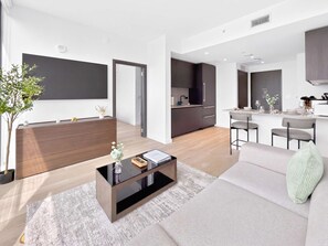 A modern living room with a sofa, coffee table, and a dining area with chairs. - Luxury 1BR with Skyline Views in Downtown Miami (Miami)