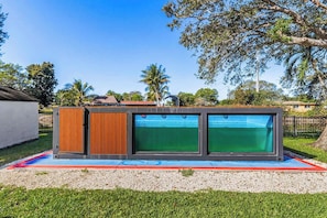 Ein moderner Poolbereich im Freien mit einem besonderen Design, umgeben von einem gepflegten Rasen und Bäumen.