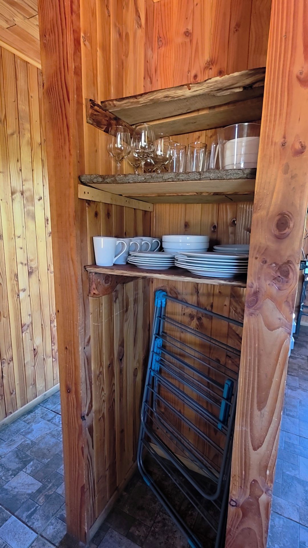 A wooden interior with shelves holding glassware and plates.